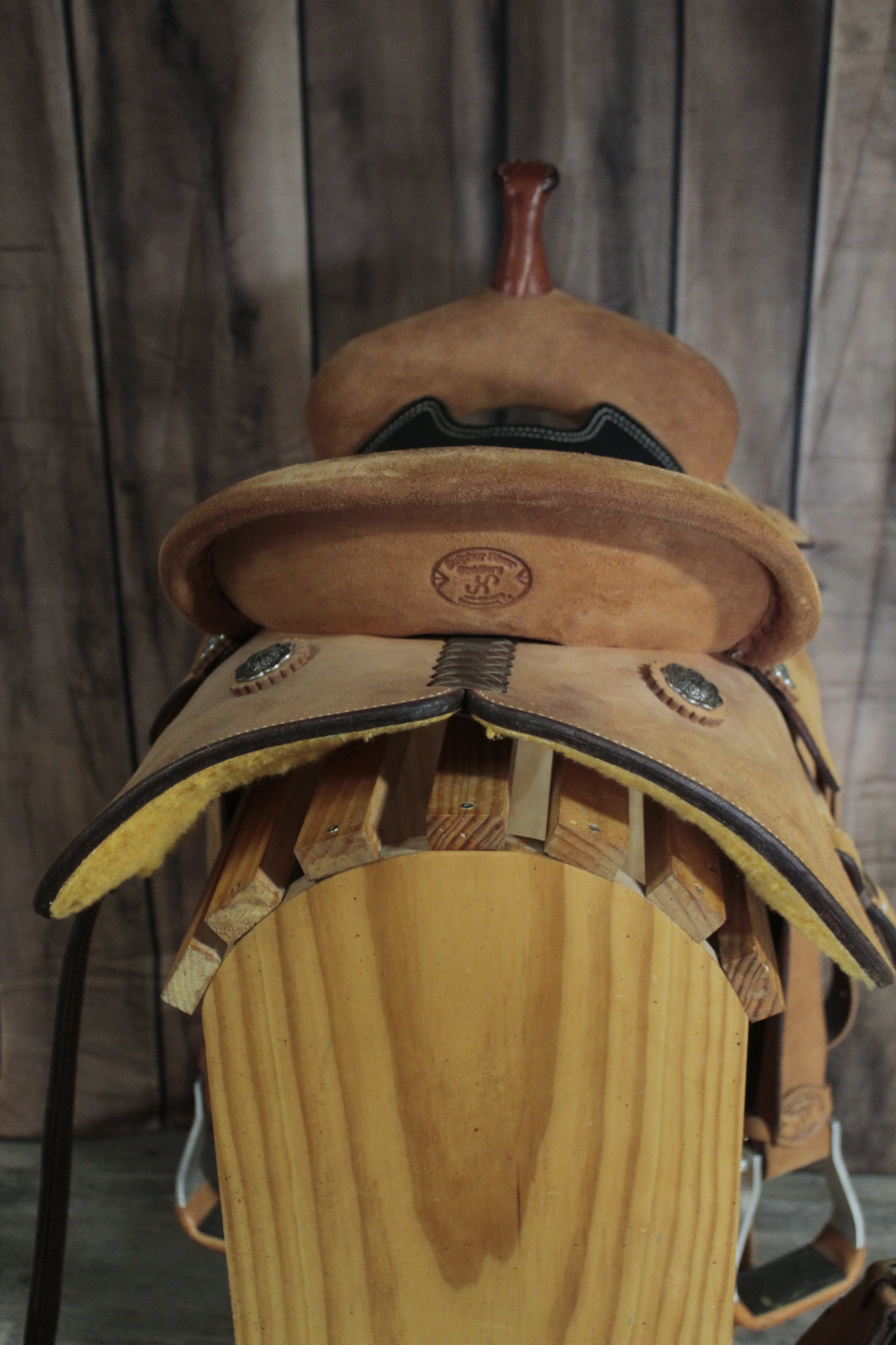 Close-up of a wooden horse saddle with leather straps on a wooden background