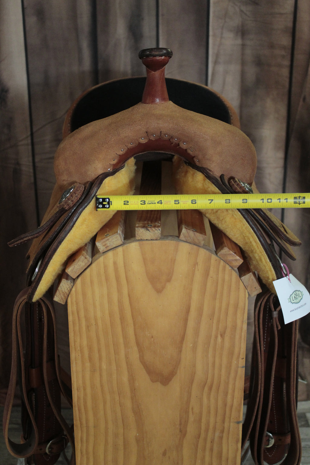 Brown leather saddle with a measuring tape on a wooden surface