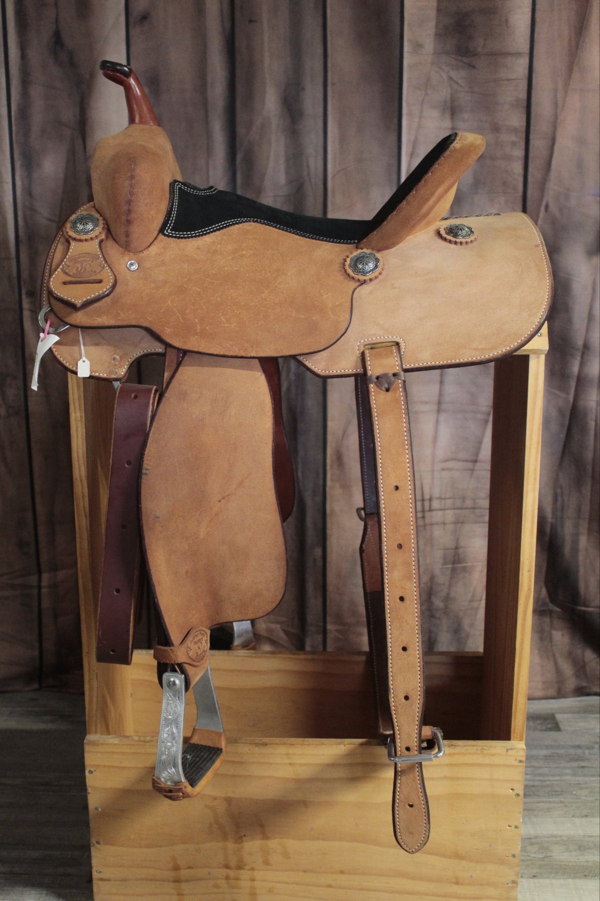 Brown leather saddle on a wooden block against a wooden background